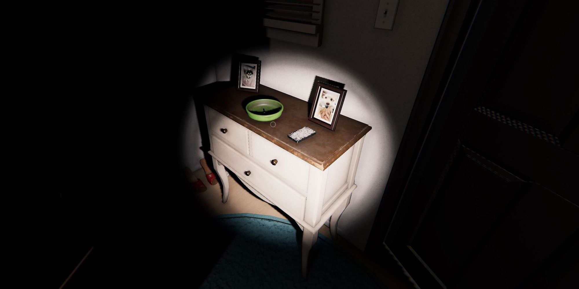 Изображение показывает коробку с картами Таро на деревянном комоде рядом с входной дверью в Edgefield House в игре Phasmophobia. На этом комоде также находятся две фотографии и зеленая миска.