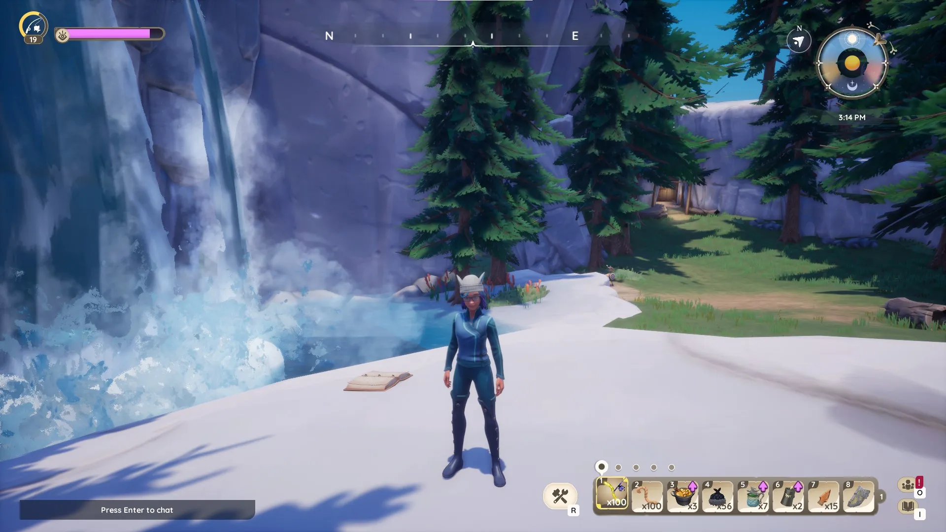 Avatar de Palia de pie cerca de una cascada con un libro abierto en el suelo. Se pueden ver pinos a lo lejos.