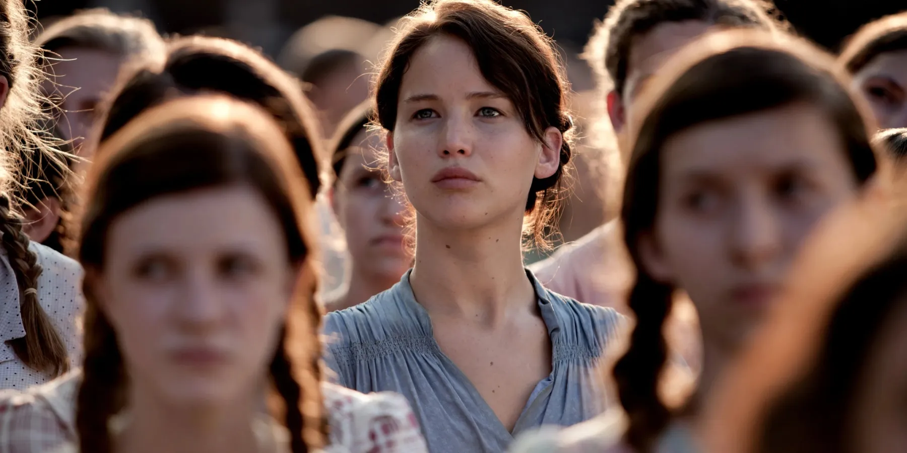Katniss Everdeen (Jennifer Lawrence) se tenant avec d'autres habitants du district 12 dans les Hunger Games