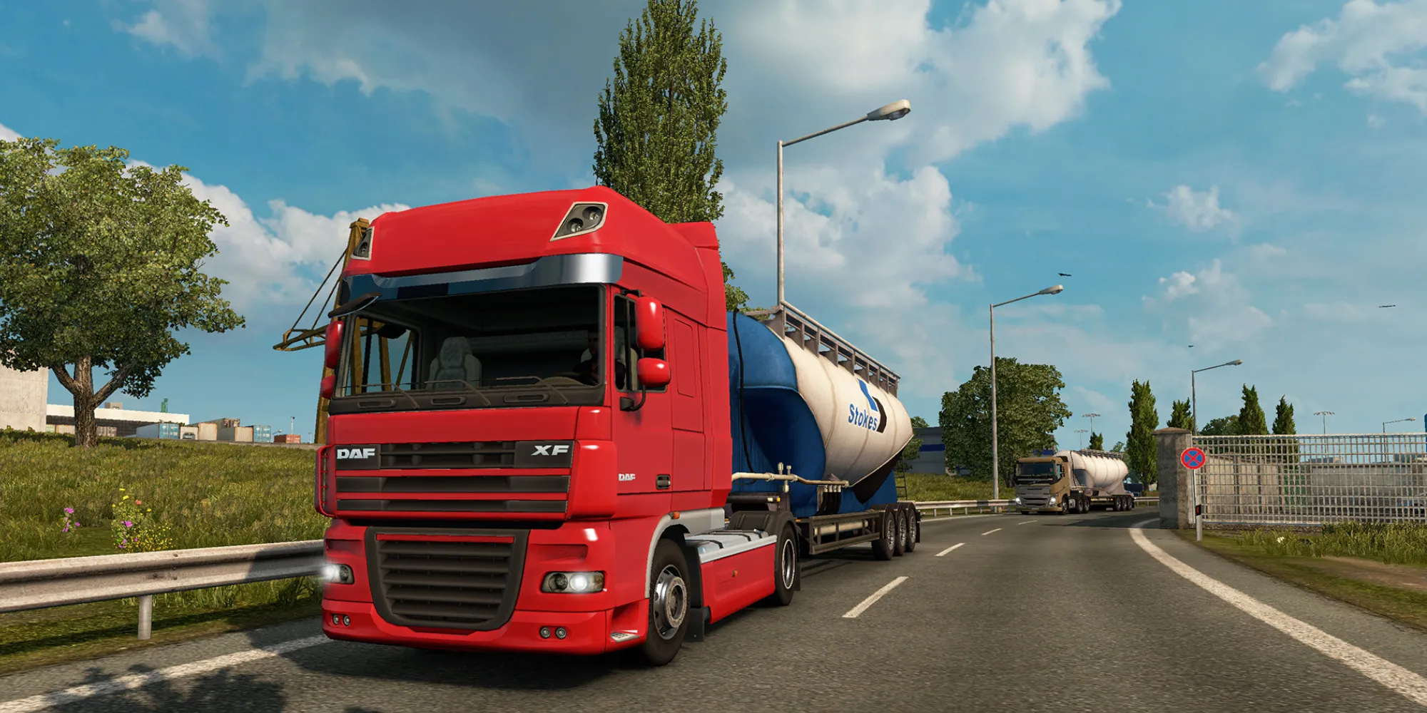 Un camion rouge tire une remorque-citerne de gaz le long d'une route urbaine dans Euro Truck Simulator 2
