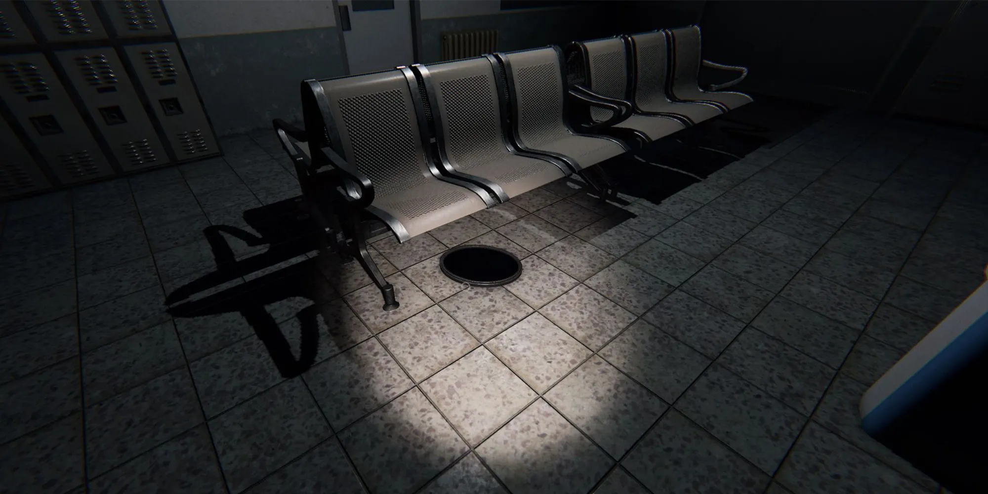 图片展示了Phasmophobia中监狱的地板下一排白色椅子上的一个闹鬼镜子。