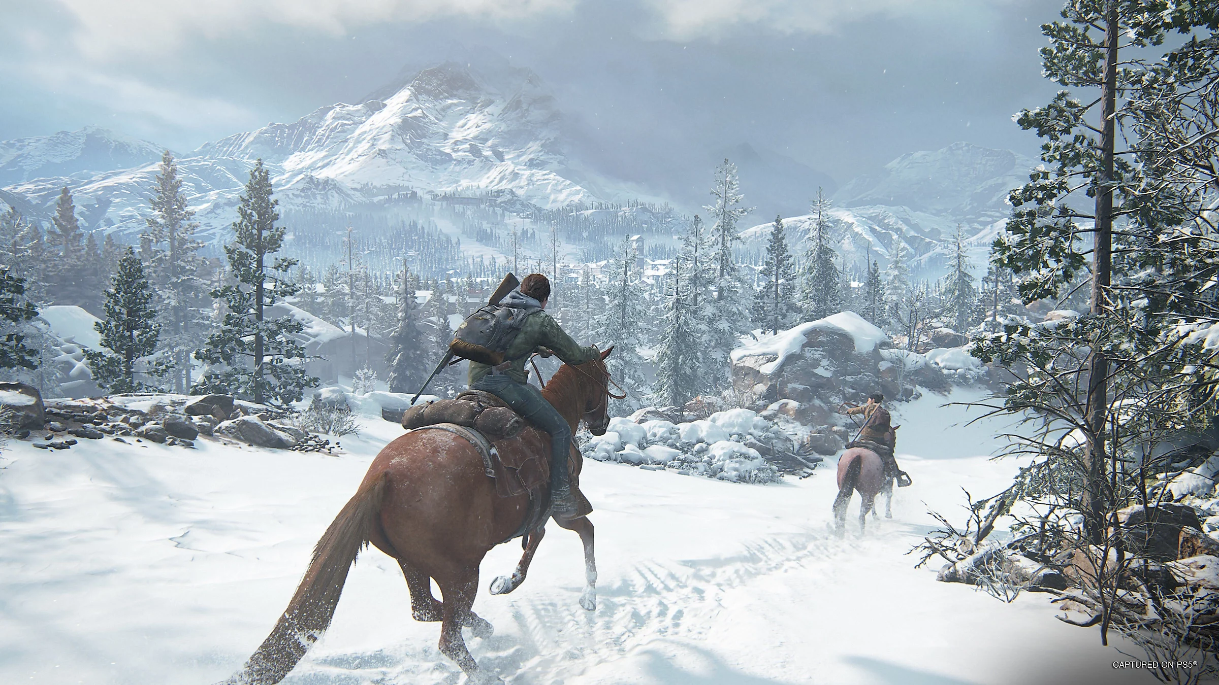 Ellie e Dina in The Last of Us Part 2 Remastered. Sono in sella a cavallo attraverso la neve