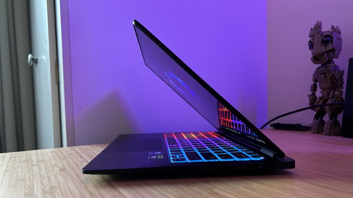 Laptop para juegos HP Omen Transcend 14 medio cerrada sobre un escritorio de madera con iluminación RGB y display activado