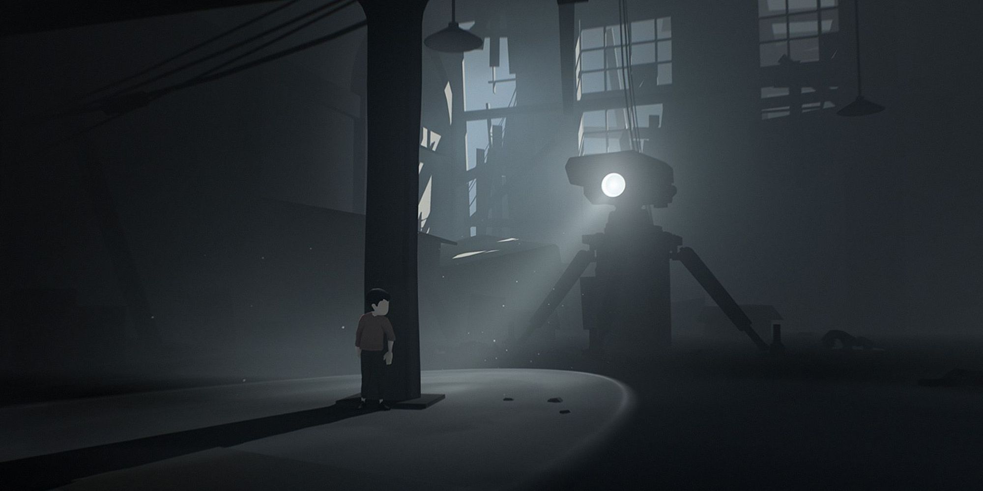Gameplay d'Inside montrant un grand robot avec une lumière regardant une colonne derrière laquelle se cache le joueur dans un entrepôt sombre