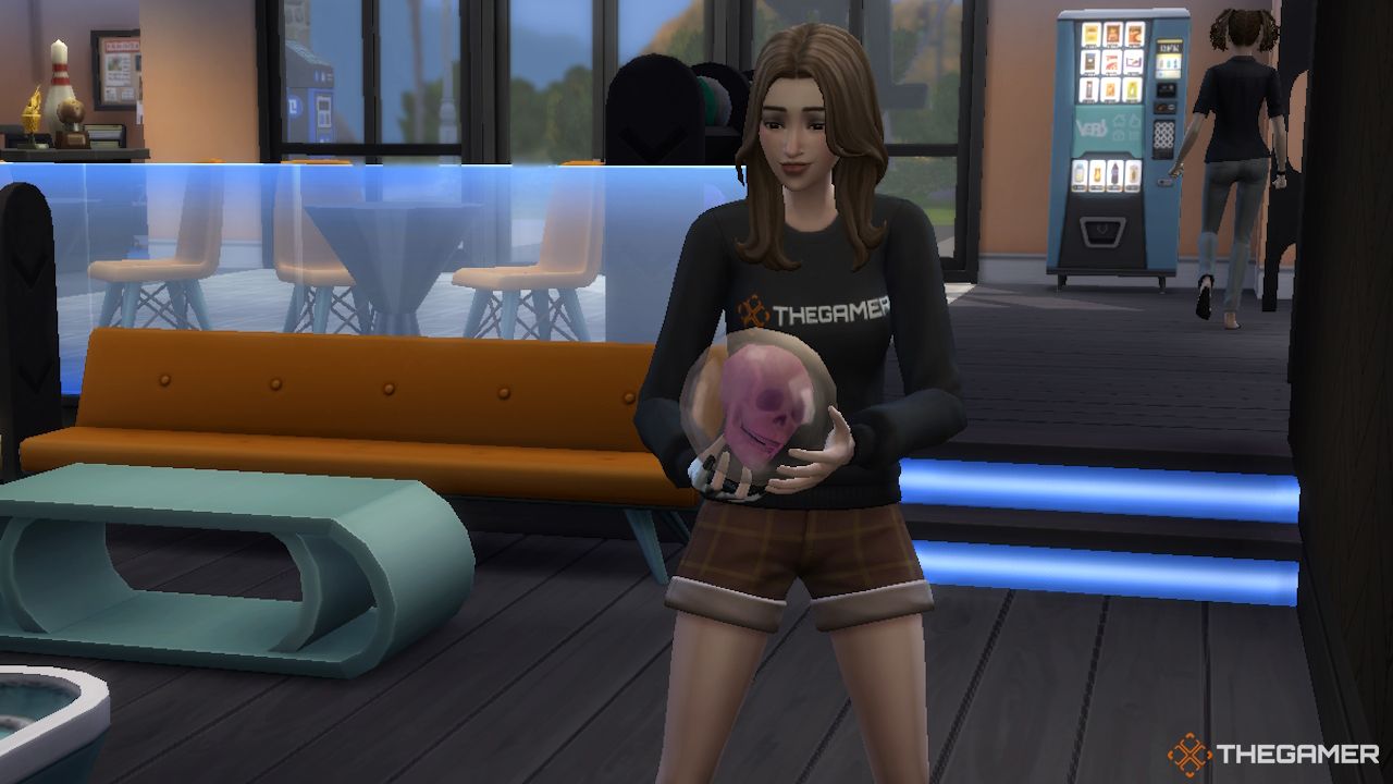 Женский Сим держит в руках прозрачный боулинг шар с изображением черепа в Sims 4