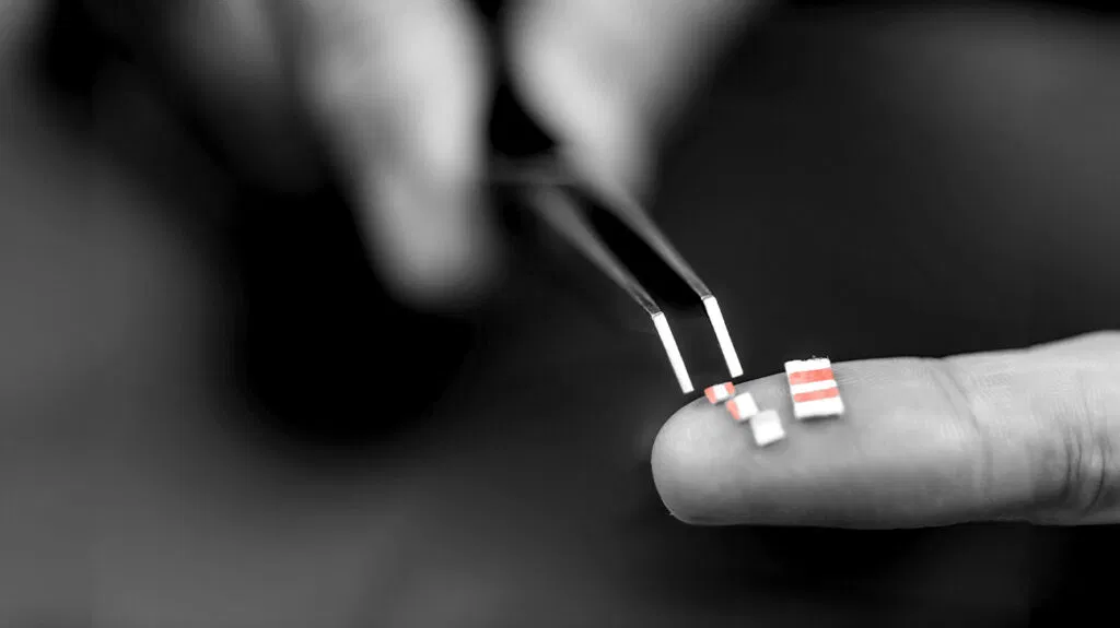 Une personne tenant des microdoses de LSD avec une paire de pinces sur leurs doigts
