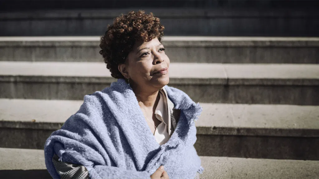 photo d'une femme noire plus âgée portant un châle bleu regardant au loin
