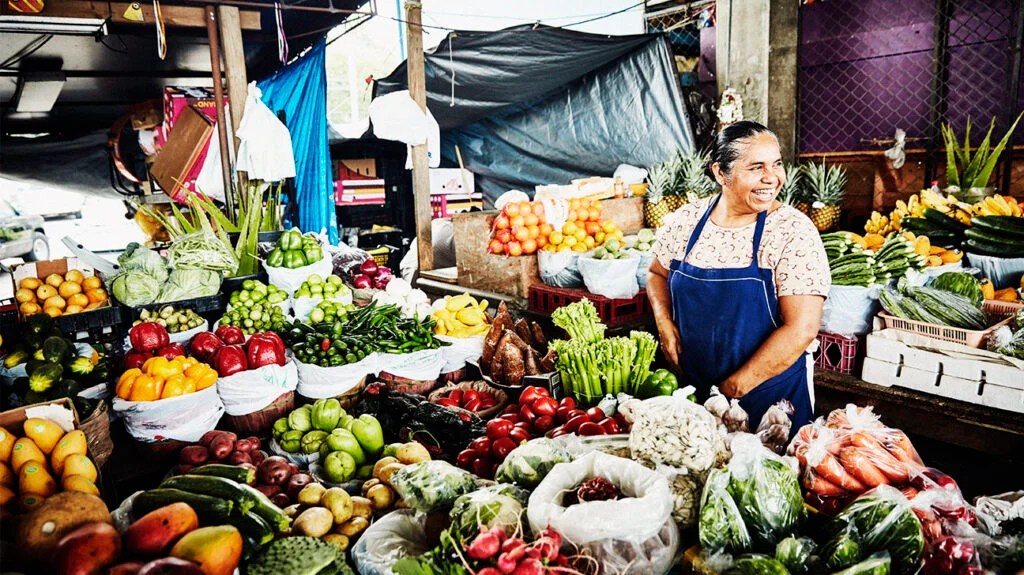 Vendeuse de fruits riant travaillant sur un stand dans un marché