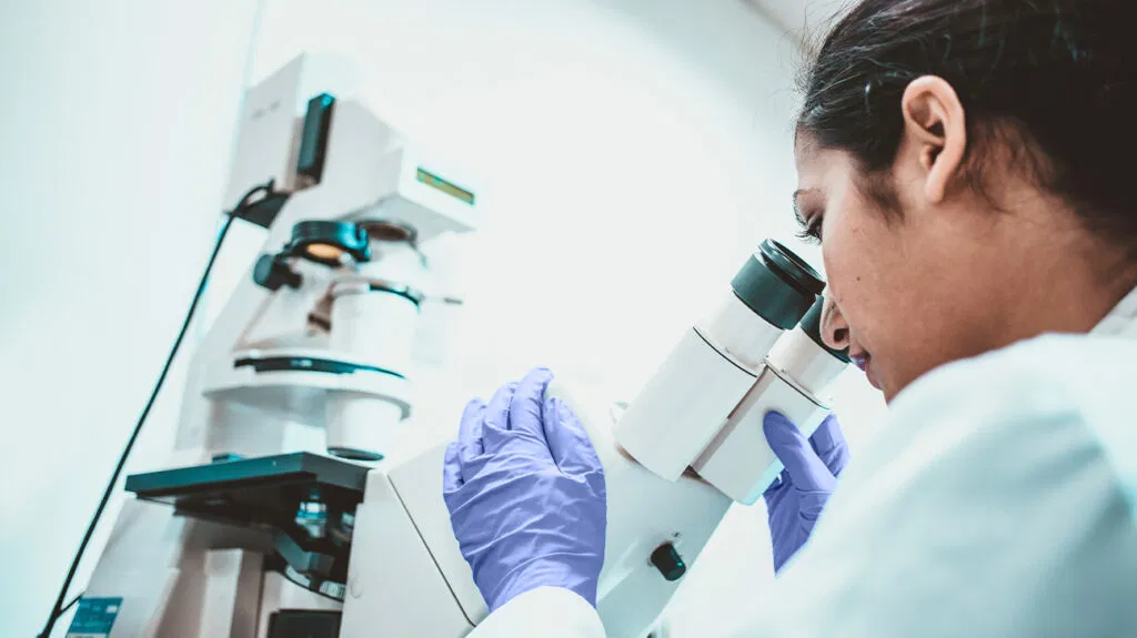 Un ricercatore sul cancro guarda in un microscopio