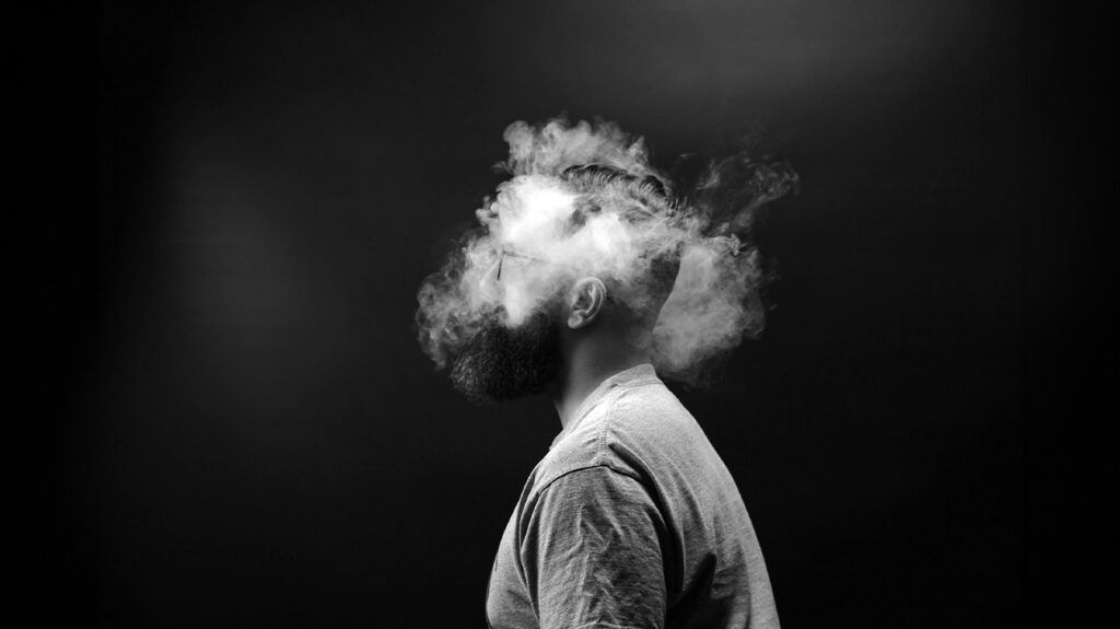 Photo en noir et blanc montrant la tête d'une personne entourée de fumée