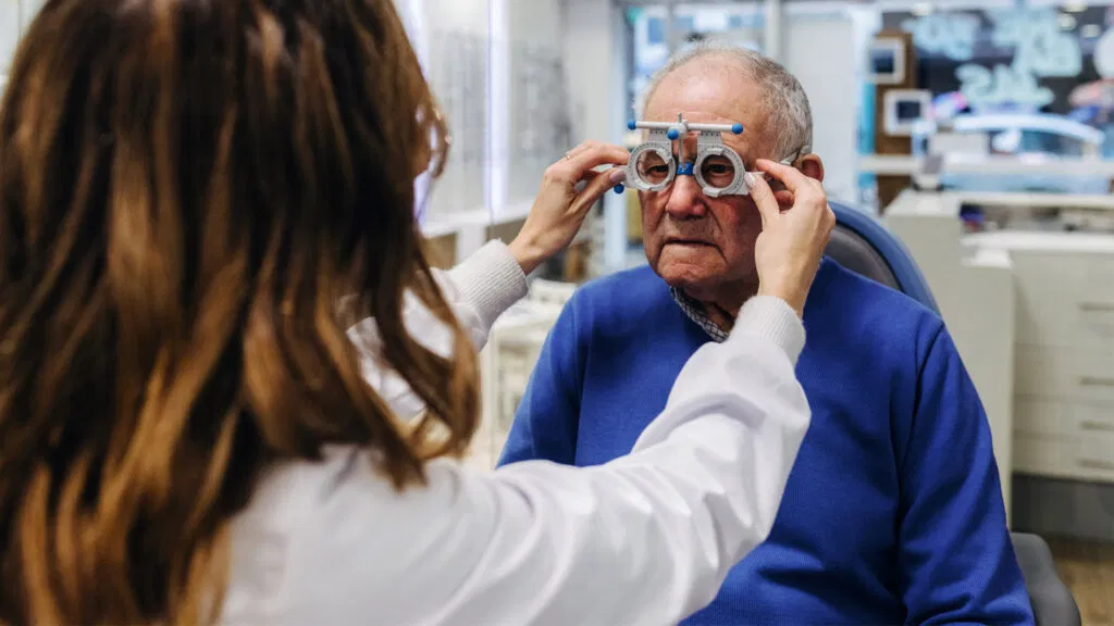 Un tecnico controlla la vista di un uomo anziano