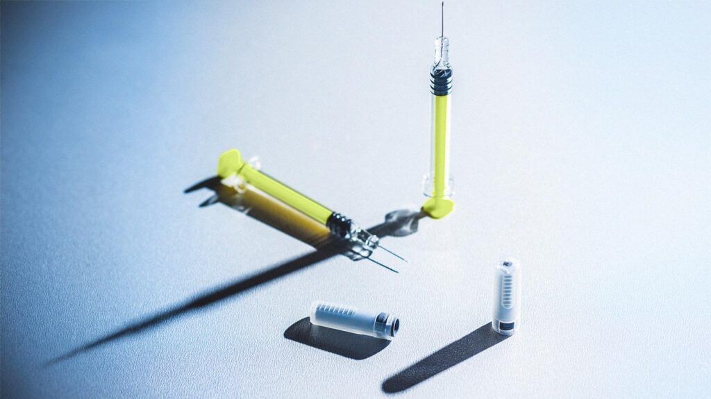 photo de deux seringues jaunes et deux flacons de vaccin