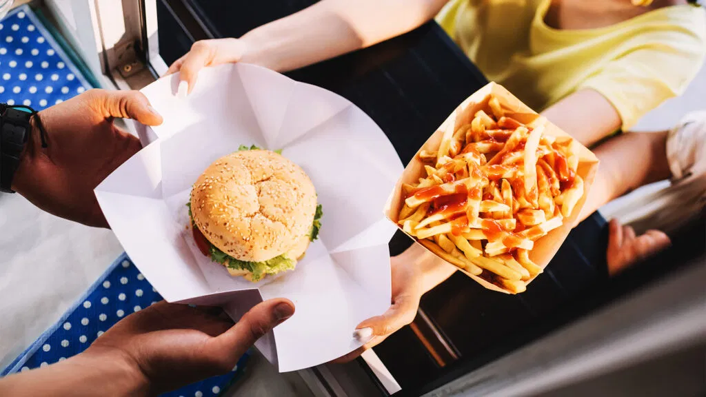 Un serveur de nourriture remet un hamburger et des frites à un client