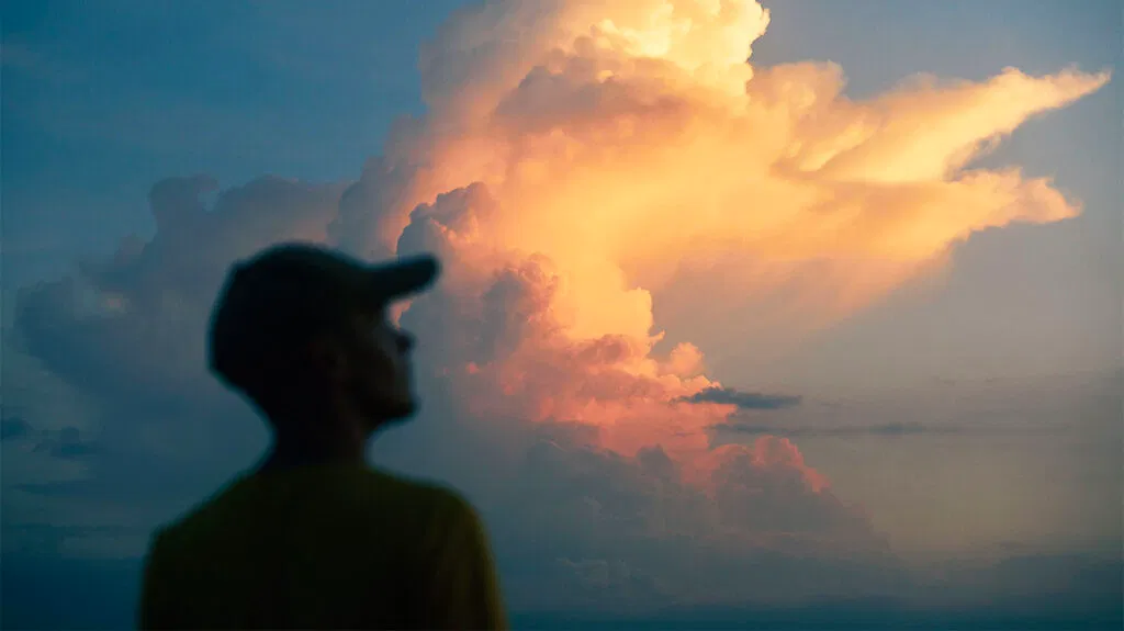 Homme contemplant les nuages orange