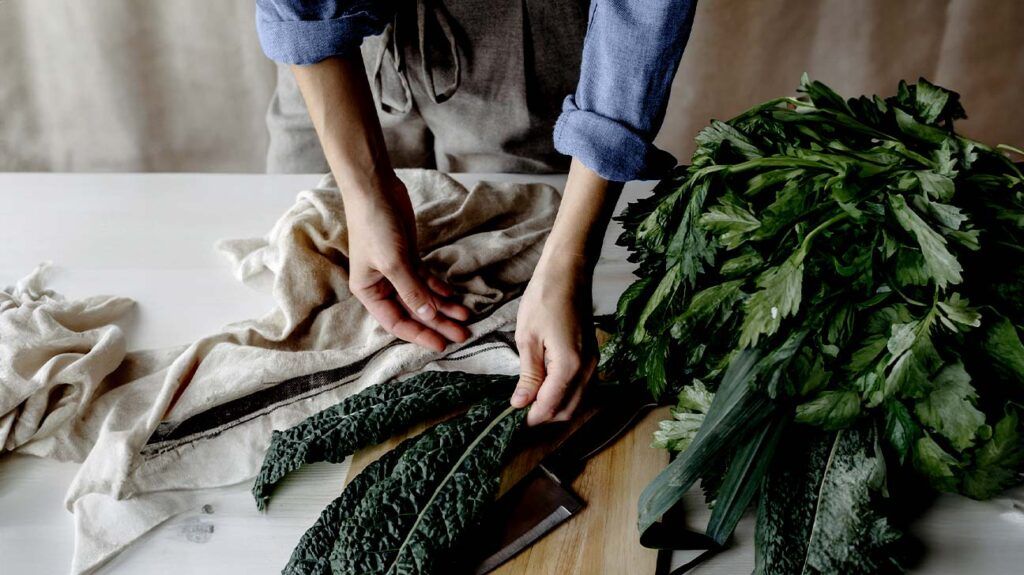 Close-up of the person’s hands as they prepare kale