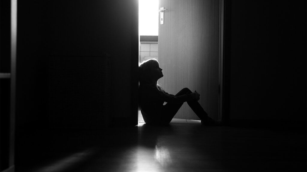 bambino seduto in una porta di un corridoio buio