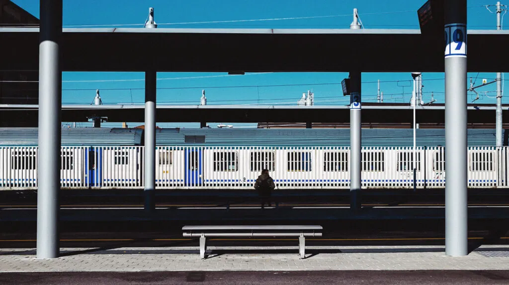 Un hombre sentado afuera en una estación de tren