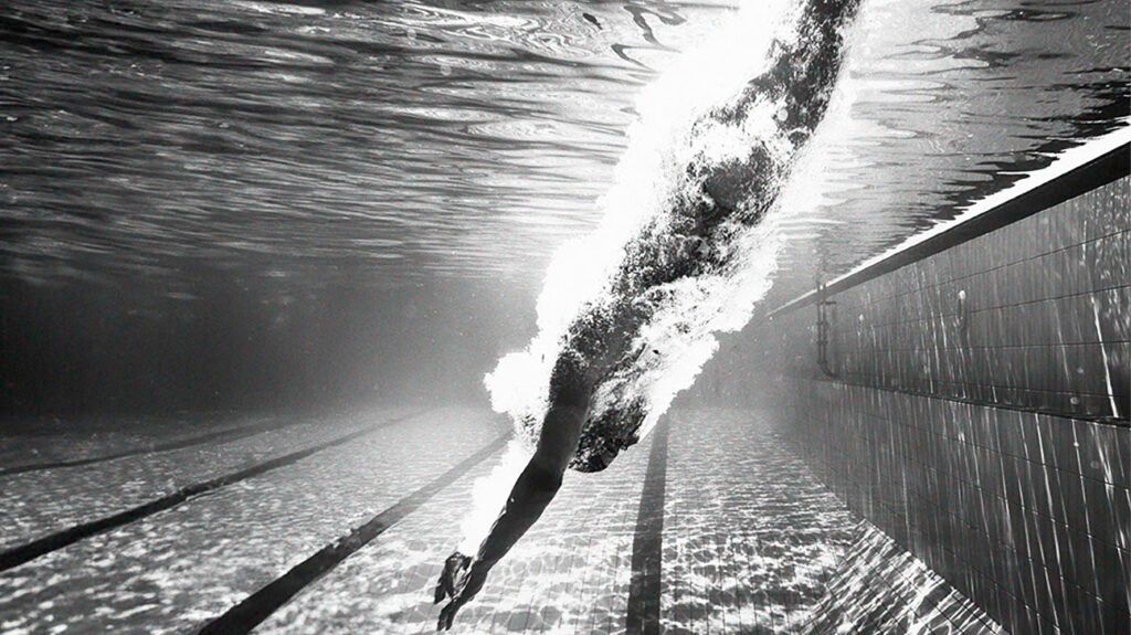 Una foto sottomarina di una donna che si tuffa in una piscina