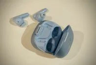 Los auriculares Soundcore fuera de su estuche (ambos de color azul claro) en una superficie blanca