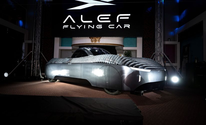 Alef Aeronatic’s ‘flying car’ displayed in a showroom. The car has a white and grey chasis and a black screened central cabin for passengers
