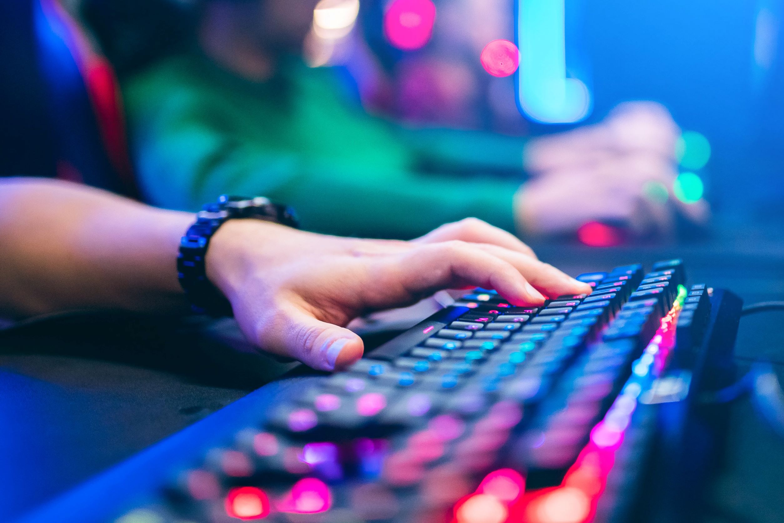 Close-up de um jogador usando um teclado mecânico com iluminação RGB