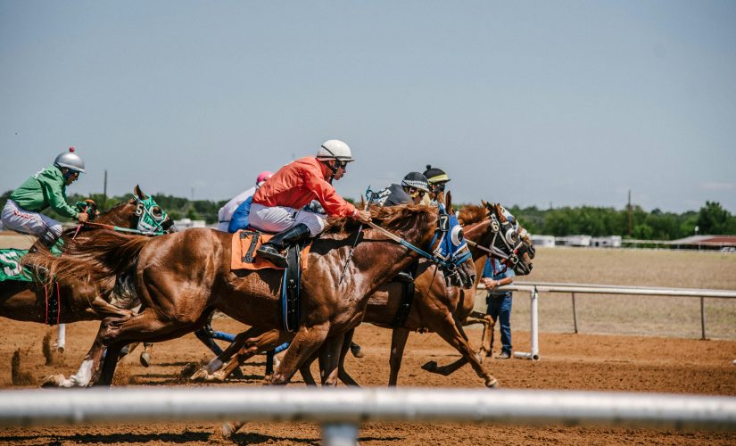 马匹赛马的图片，包括赛马场上的骑师 - Flutter Entertainment宣布与法国品牌Pari Mutuel Urbain（PMU）延长合作伙伴关系