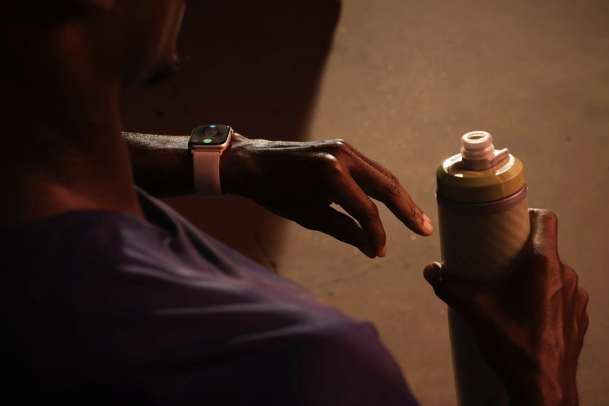 Apple Watch Series 9 on man’s wrist as he double taps with a drink in his other hand