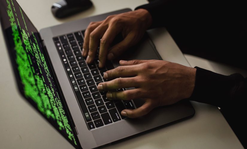 Mãos de um homem hacker em um laptop de tela verde