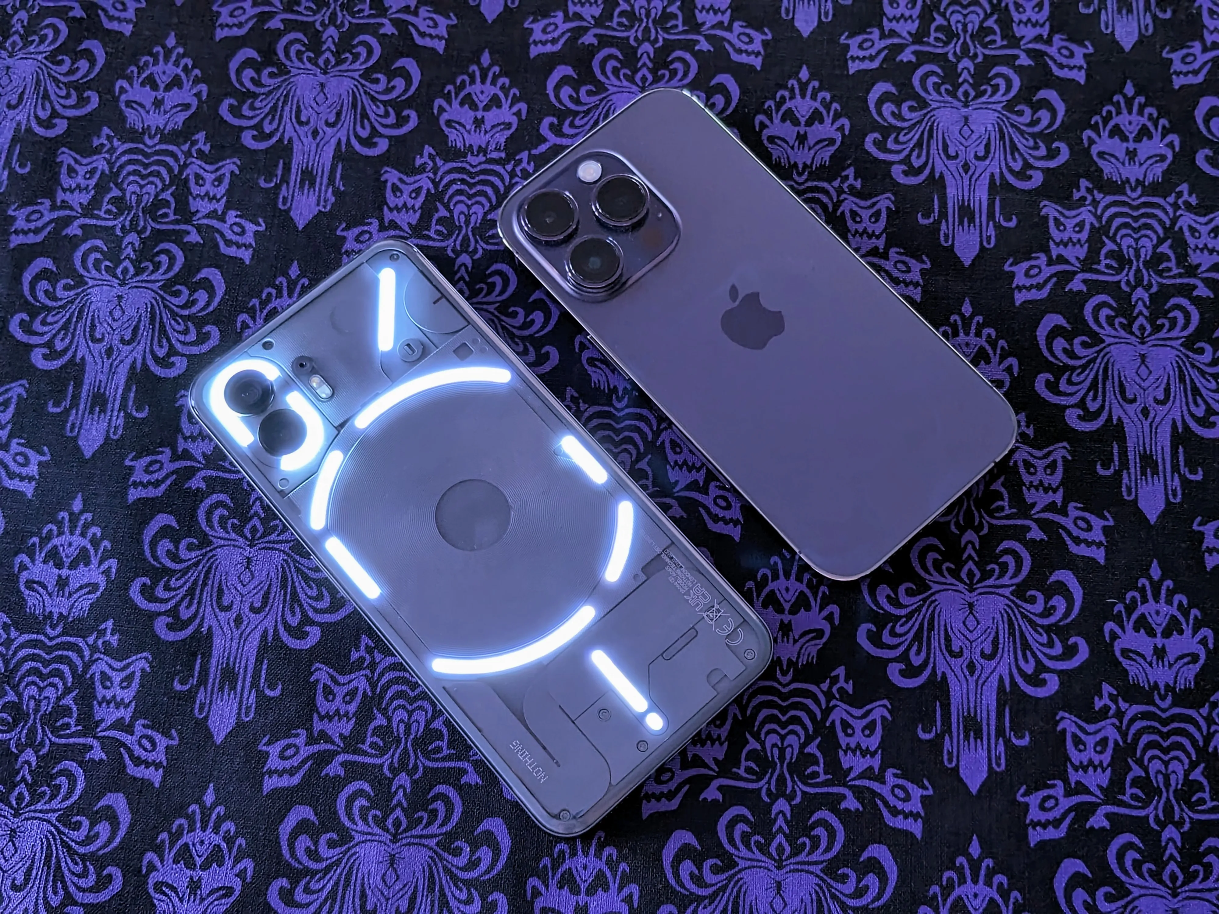 Nothing Phone 2 illuminato accanto a un iPhone 14 Pro.
