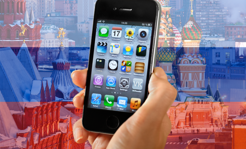 苹果向俄罗斯支付了1370万美元的反垄断罚款。图片显示iPhone举在透明的俄罗斯国旗和克里姆林宫前