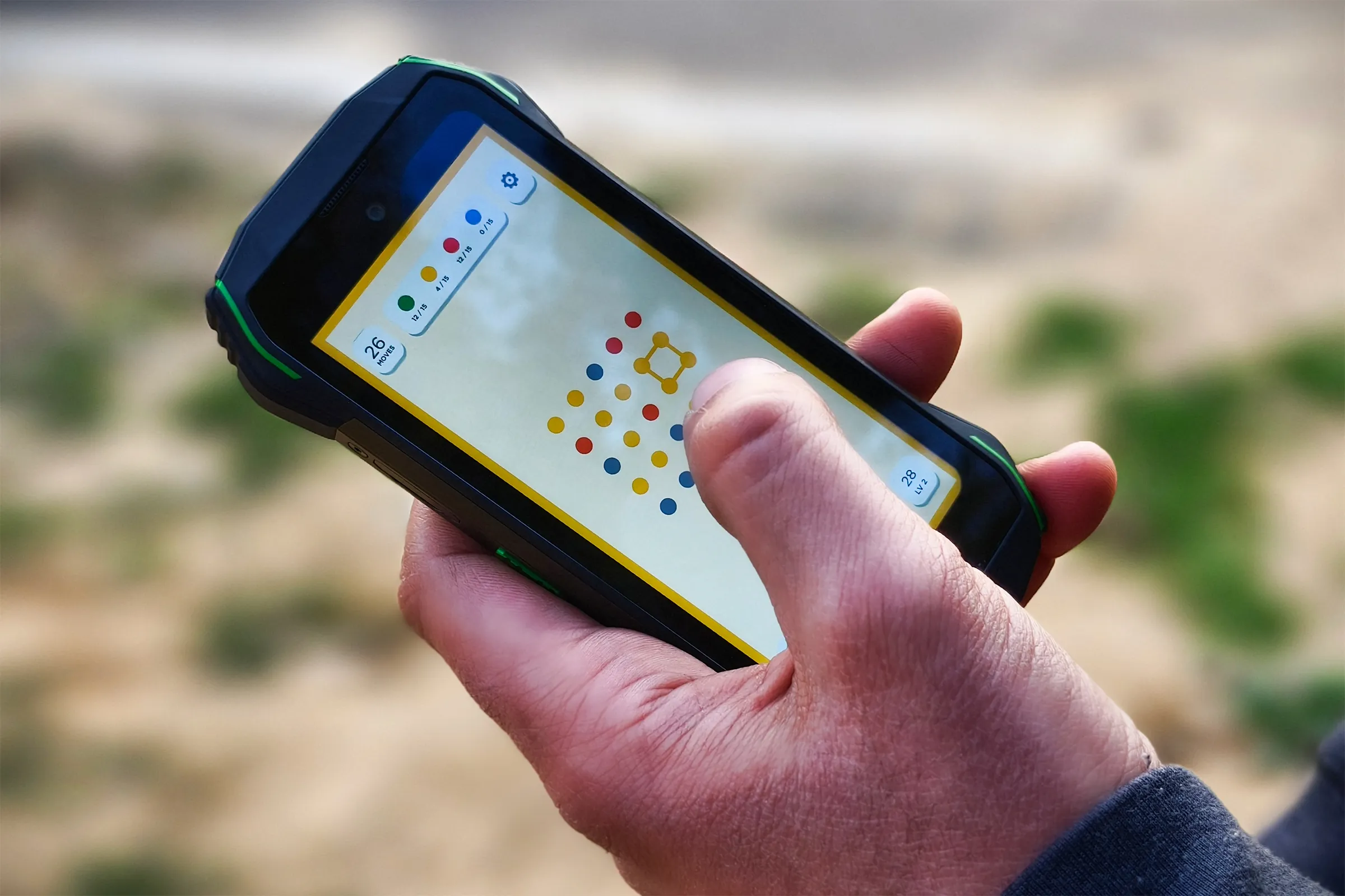 Juego Two Dots en el pequeño teléfono Android resistente Blackview N6000 sostenido en la mano de una persona.