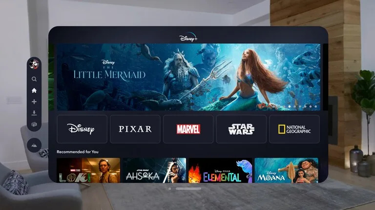 Imagem do aplicativo Disney+ para o VisionOS. Uma janela flutuante mostra o menu principal do serviço em uma sala de estar.