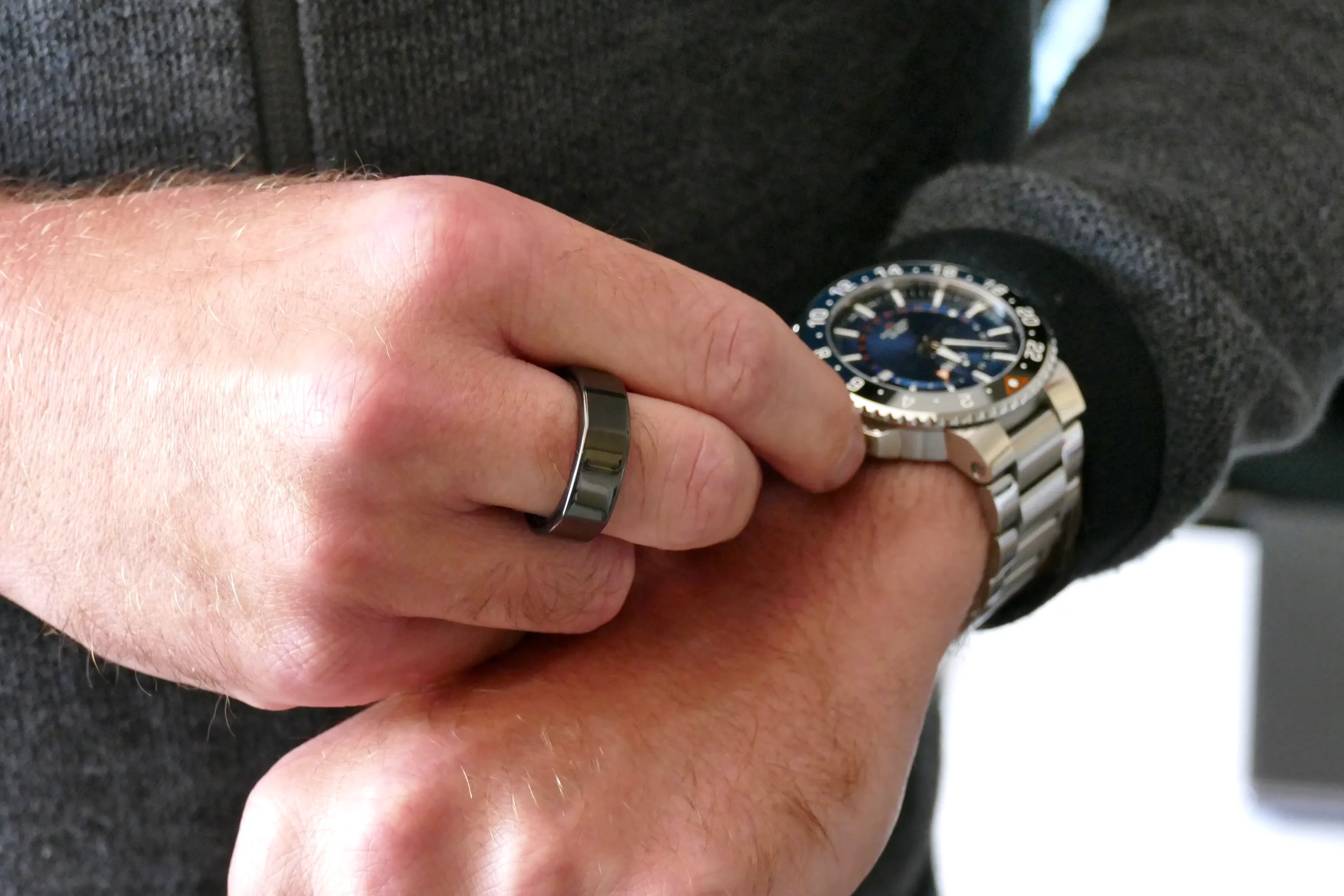 一个男士戴在手指上的 Oura 戒指，在卷动手表