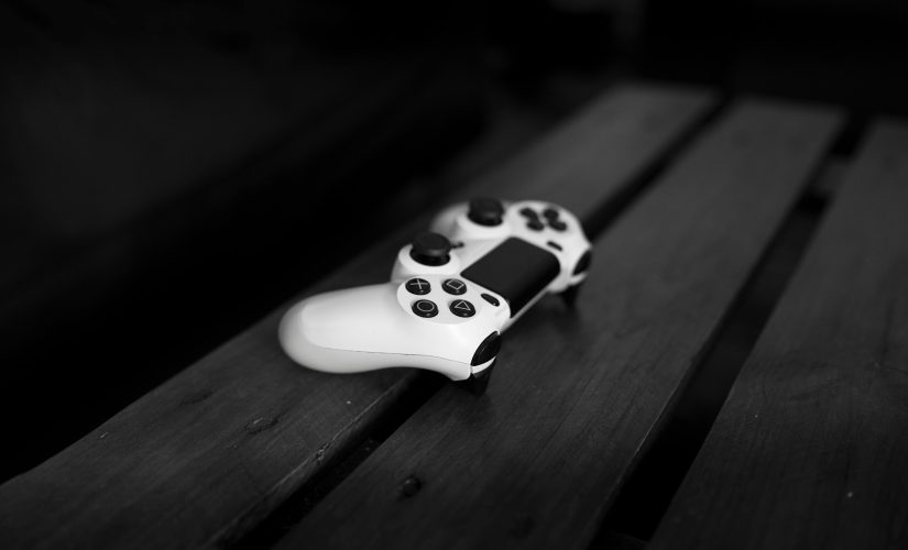 Un control de PlayStation blanco sobre una mesa de madera negra sin nada más en la toma