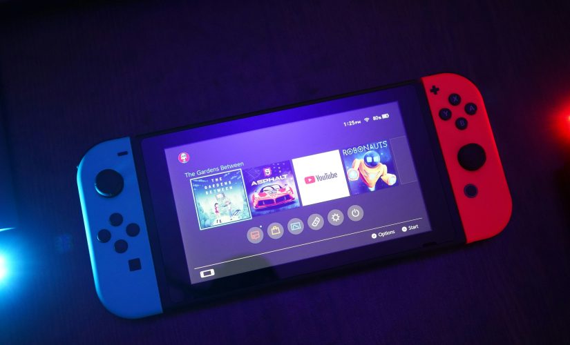 Nintendo Switch сине-красного цвета включен в темной комнате.