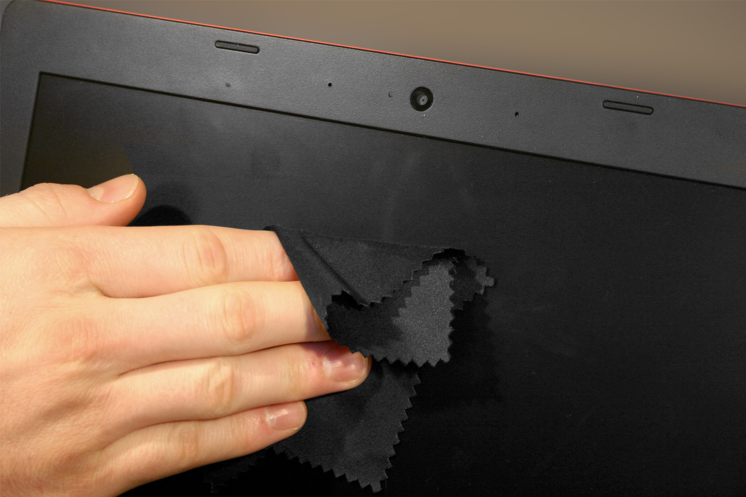 Человек чистит экран ноутбука микрофибровой тканью.