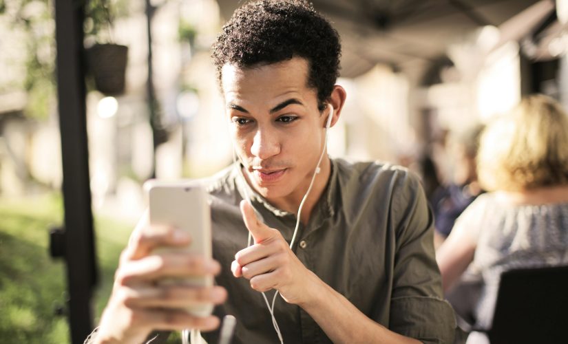 Um jovem está se comunicando com outra pessoa em seu smartphone