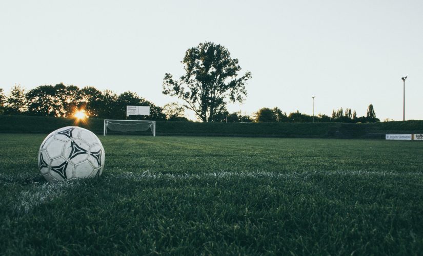 Футбольный мяч на траве на закате