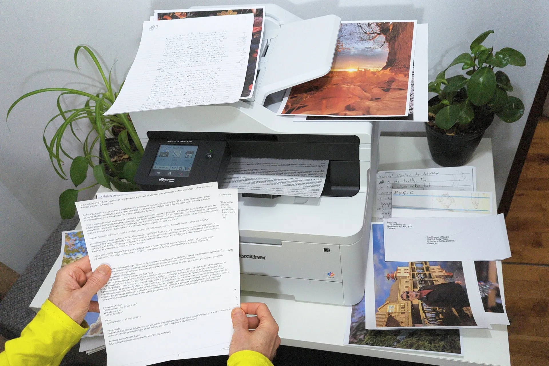 Принтер Brother MFC-L3780 CDW цветного лазера окружен картинами, черно-белыми и цветными документами.