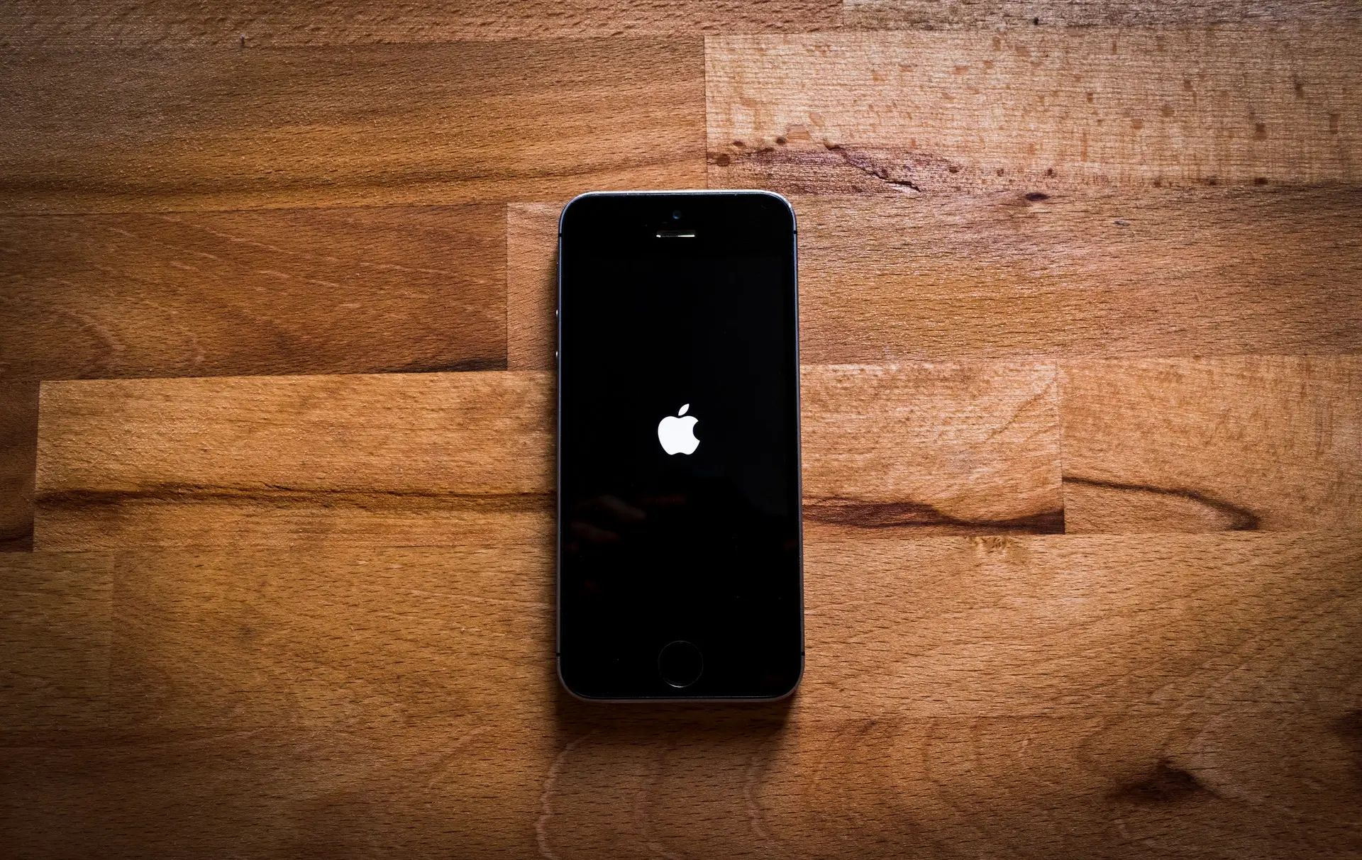 Um iPhone deitado sobre uma mesa de madeira.