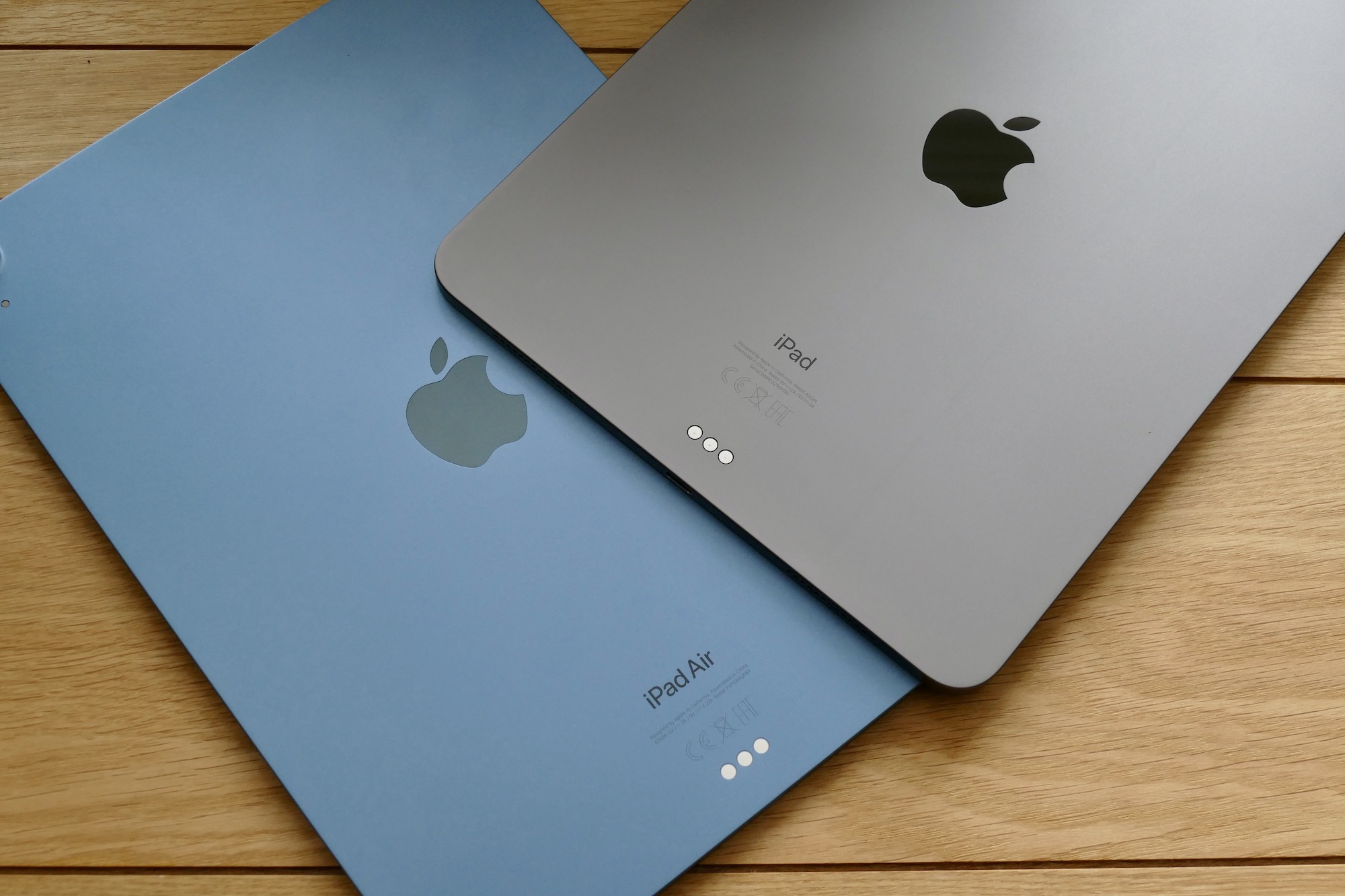 Apple의 iPad Air와 iPad Pro의 뒤편, 테이블 위에 놓인 태블릿들.