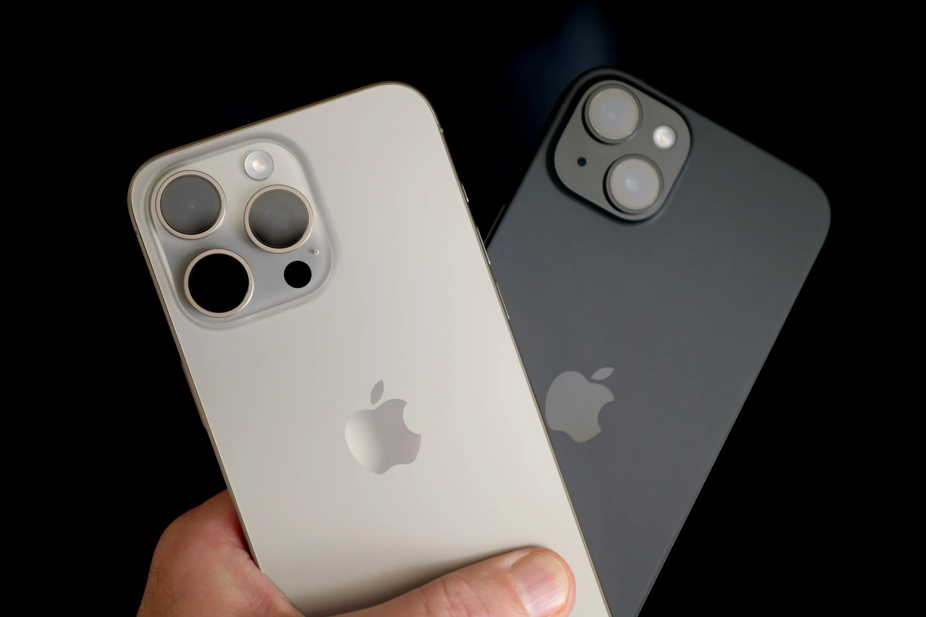 Человек, держащий Apple iPhone 15 Plus и Apple iPhone 15 Pro Max.